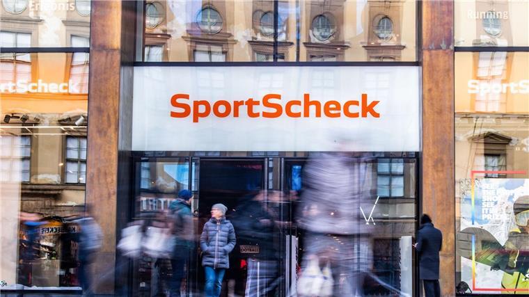 SportScheck-Geschäfte schließen: 200 Arbeitsplätze weniger Personen gehen an einer Sportscheck-Filiale in der Münchener Fußgängerzone vorbei.