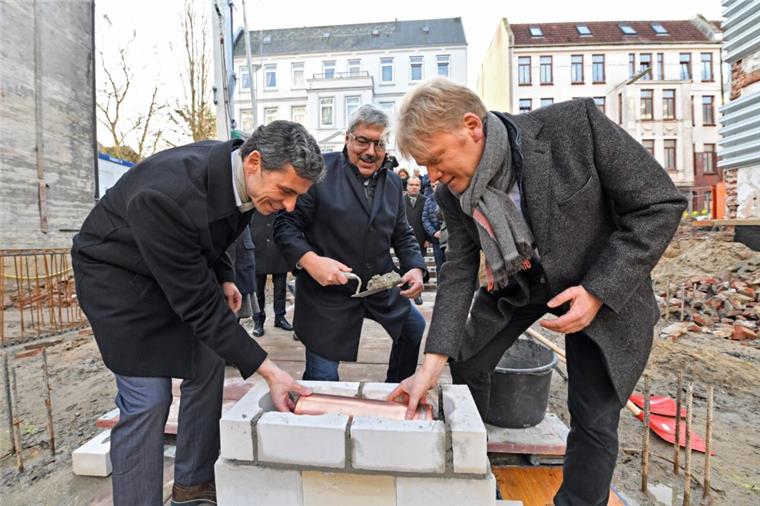 Peter Ritzenhoff, Melf Grantz und Sieghard Lückehe (von links) mauern die Zeitkapsel bei der Grundsteinlegung ein.