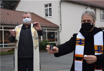 Pfarrer Karl Jasbinschek und Pastorin Heike Boelmann-Derra zeigen Streichholzschacheln und LED-Kerzen, die beim ökumenischen Freiluft-Gottesdienst an Heiligabend genutzt werden.