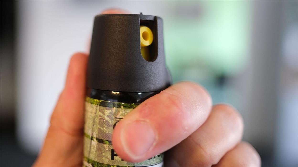 Eine Hand hält eine Kartusche mit Pfefferspray.
