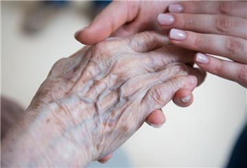 Alt und Jung: Eine Pflegerin hält die Hand einer Bewohnerin in einem Seniorenzentrum.