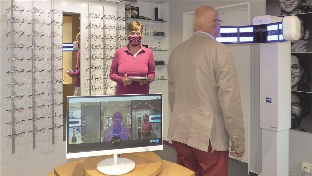 Optikerin mit Mundschutz präsentiert moderne Technik.