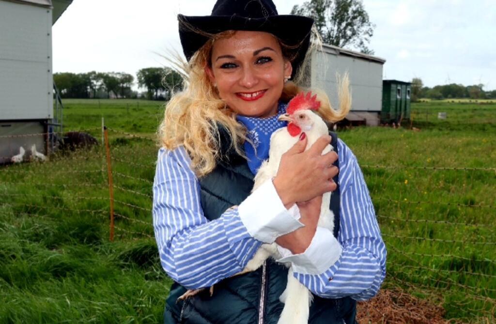 Annika Wöstehoff-Haas mit einem weißen Huhn auf dem Arm.
