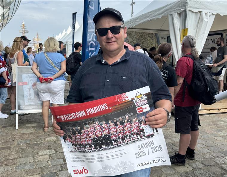 Ein Mann hält ein Eishockeyposter in der Hand.