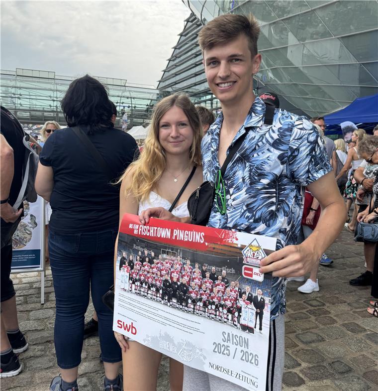 Ein Mann und eine Frau halten ein Eishockeyposter.
