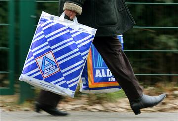 Die Kundin einer Aldi-Filiale trägt am 26.03.2013 in Essen (Nordrhein-Westfalen) in einer Einkaufstüte von Aldi-Nord und einer von Aldi-Süd ihre Einkäufe. 