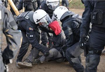 Polizeibeamte entfernen einen Klimaschutzaktivisten aus einer Straßenblockade am Rand der Ortschaft Lützerath.