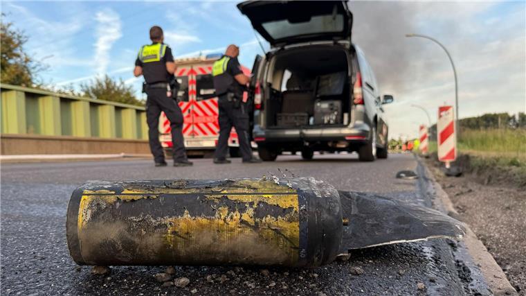 Hunderte Feuerwehrleute löschen Großbrand in Hamburg Polizisten stehen hinter einem Metallbehälter. Trümmerteile sollen bei dem Brand Hunderte Meter weit geflogen sein.