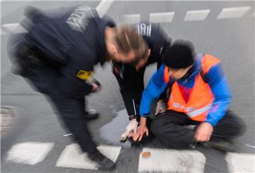 Polizisten versuchen festgeklebte Hände von Aktivisten der Gruppierung „Letzte Generation“ von der Straße abzulösen. Künftig sollen solche Aktionen der Aktivisten weniger werden. (Archivbild)