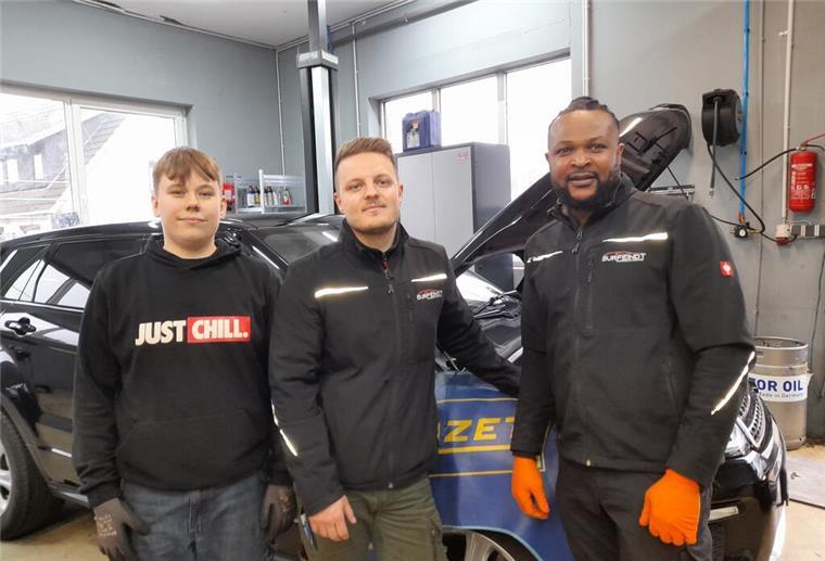 Bei Burfeindt Fahrzeugtechnik gibt es das Rundum-sorglos-Paket Drei Männer stehen in einer Werkstatt vor einem Auto.