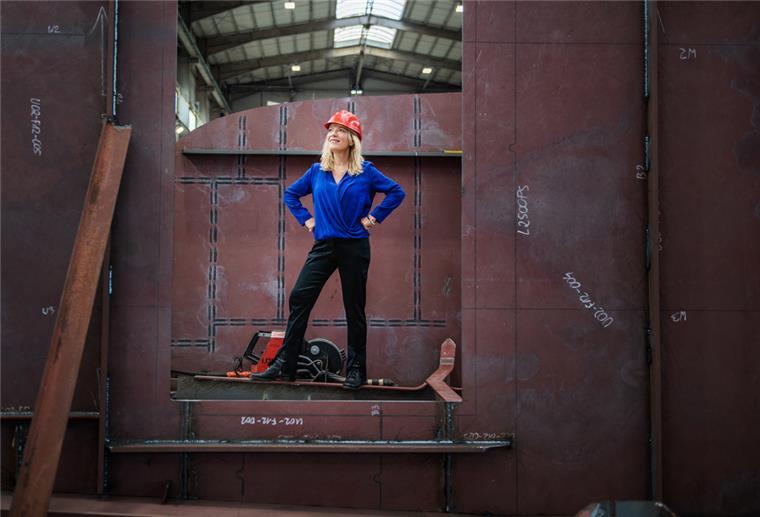 Eine Frau steht auf einer Werft im Kiel eines neuen Schiffes.