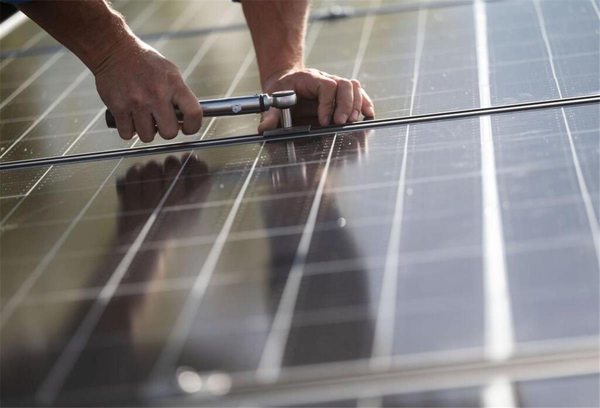  Mitarbeiter einer Firma montieren Photovoltaikmodule auf dem Dach eines Wohnhauses. 