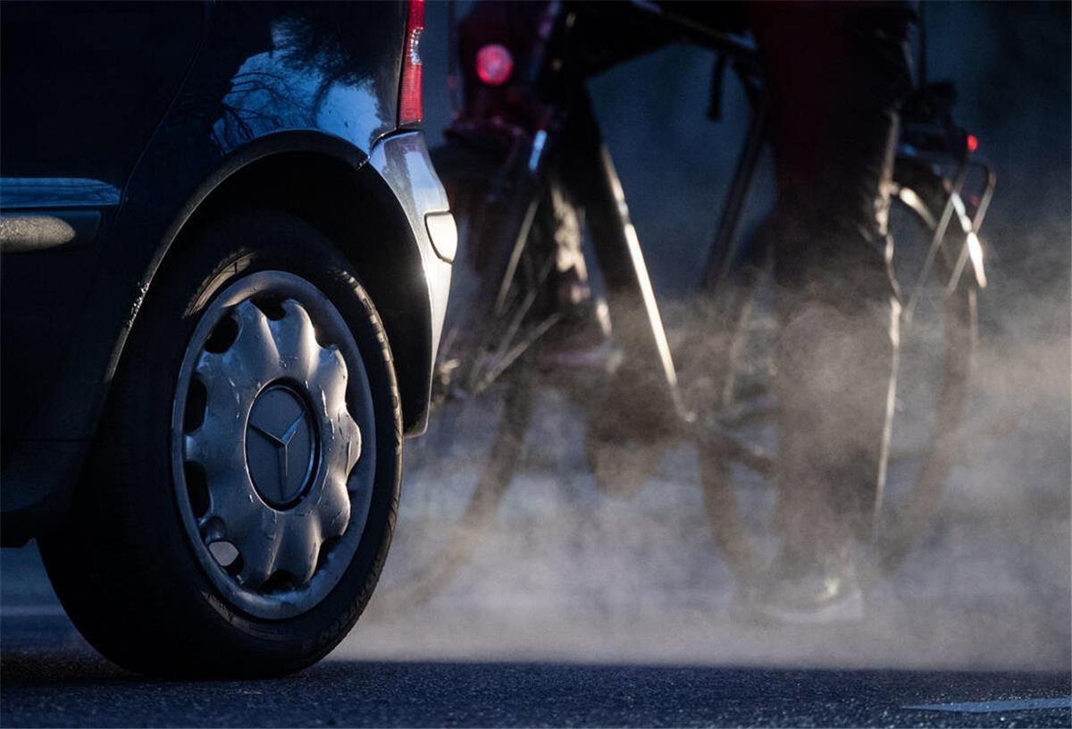 ARCHIV - 23.11.2021, Baden-Württemberg, Stuttgart: Ein Radfahrer steht neben einem Auto von Mercedes mit Dieselantrieb, dessen Abgase in der kalten Morgenluft sichtbar werden. (zu dpa: «Nur noch am Bodensee höhere Feinstaubbelastung») Foto: Marijan Murat/dpa +++ dpa-Bildfunk +++