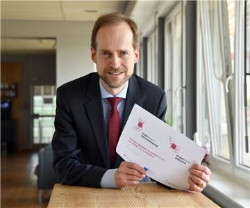 Ralf Stapp von der Bremer Aufbaubank zeigt das jeweilige Logo der Starthäuser Bremerhaven (links) und Bremen. Das Starthaus ist eine zentrale Anlaufstelle für Unternehmensgründer.
