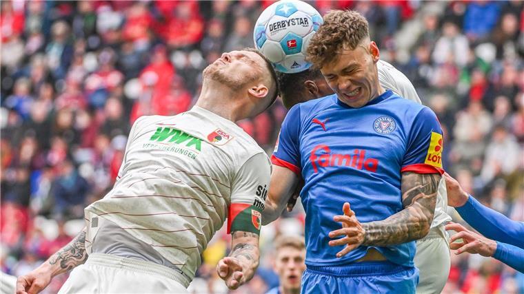Rasant ging es zu auf dem Platz. Kiels Nicolai Remberg (r) und Augsburgs Kapitän Jeffrey Gouweleeuw beim Kopfballduell.