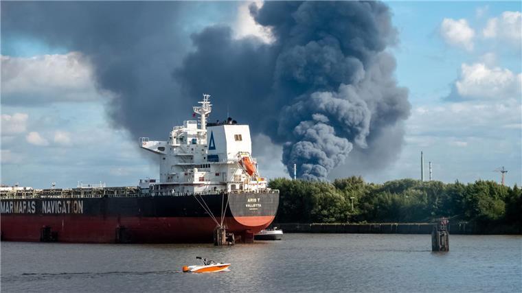 Hunderte Feuerwehrleute löschen Großbrand in Hamburg Rauch ist hinter einem Schiff zu sehen; in der Nähe des Einsatzortes fließt die Norderelbe.