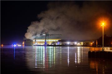 Rauch steigt über der Lürssen-Werft in Bremen-Vegesack in den Himmel. In der Werft war in der Nacht zum Freitag ein Dock samt Schiffsneubau in Flammen aufgegangen.