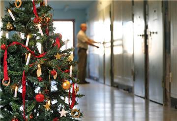 Auf einem mit einem Weihnachtsbaum geschmückten Gefängnisflur schließt ein Justizvollzugsbeamter eine Zellentür ab.