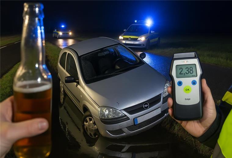 Bei Burhave: Alkoholfahrt endet im Wassergraben Ein Auto in einem Wassergraben, im Hintergrund Polizeifahrzeuge. Im Vordergrund ein Atenalkohol-Messgerät, dass die Zahl 2,38 anzeigt, und eine Flasche Bier in einer Hand.