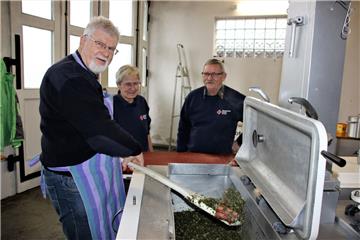 Reinhard Gebauer rührt den Grünkohl um. Dabei wird er von Erika und Erich Sommer, die als Einsatzleiter beim DRK in Schwei tätig sind, beobachtet.