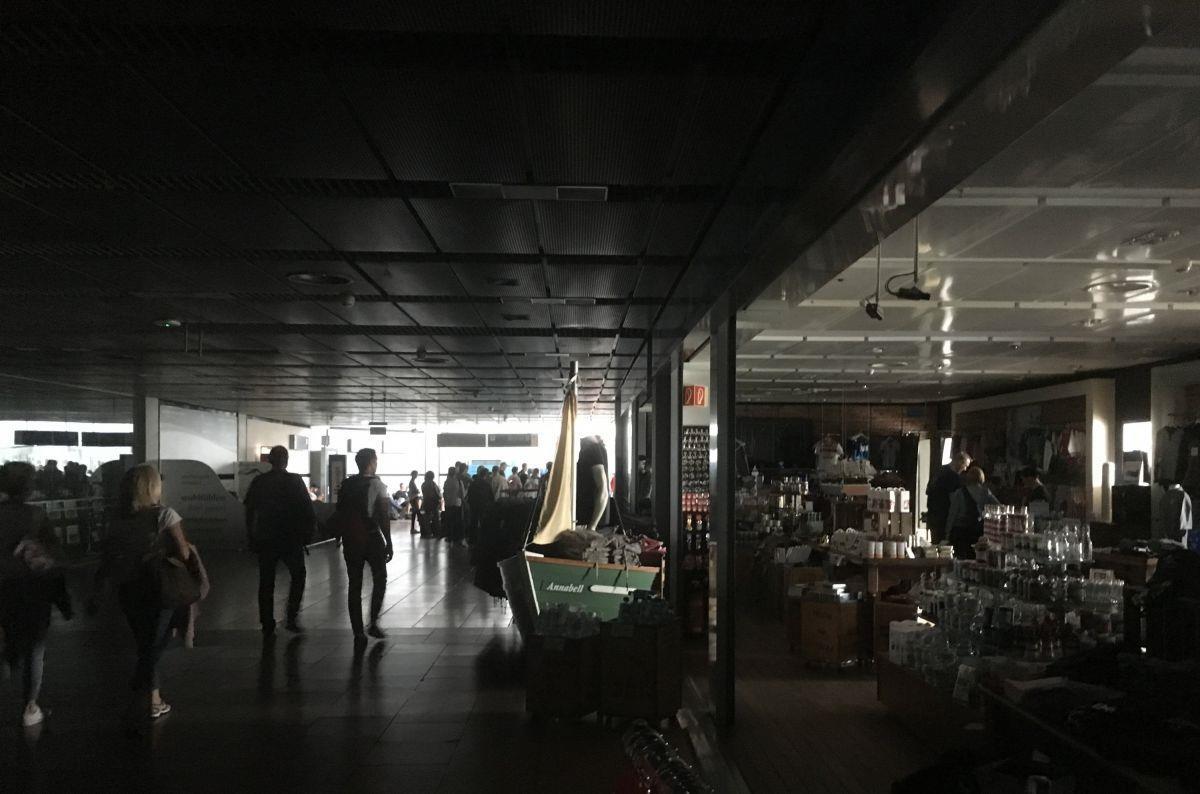 Reisende gehen während eines Stromausfalls durch den unbeleuchteten Hamburger Flughafen.

