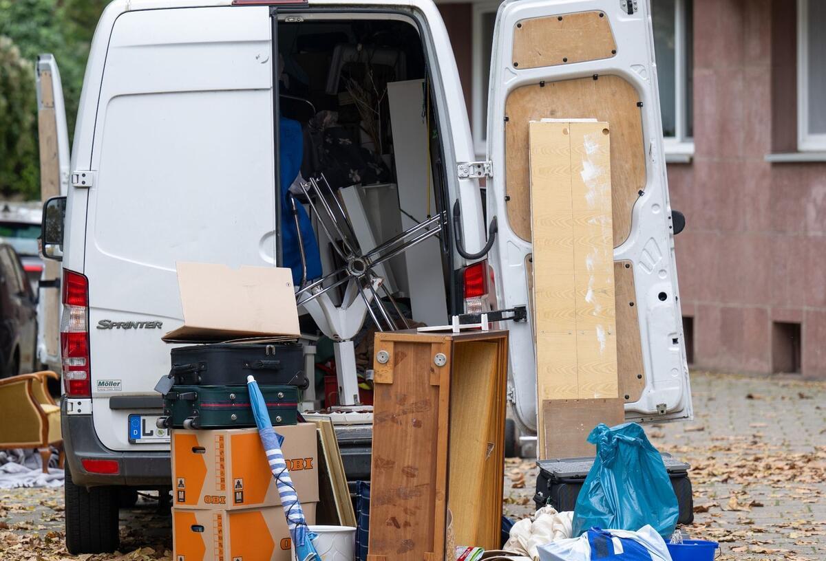 Rentenstopp droht! Vermeide diese Fehler beim Umzug Möbel und Umzugskartons stehen vor einem Transporter an einem Wohnhaus.
