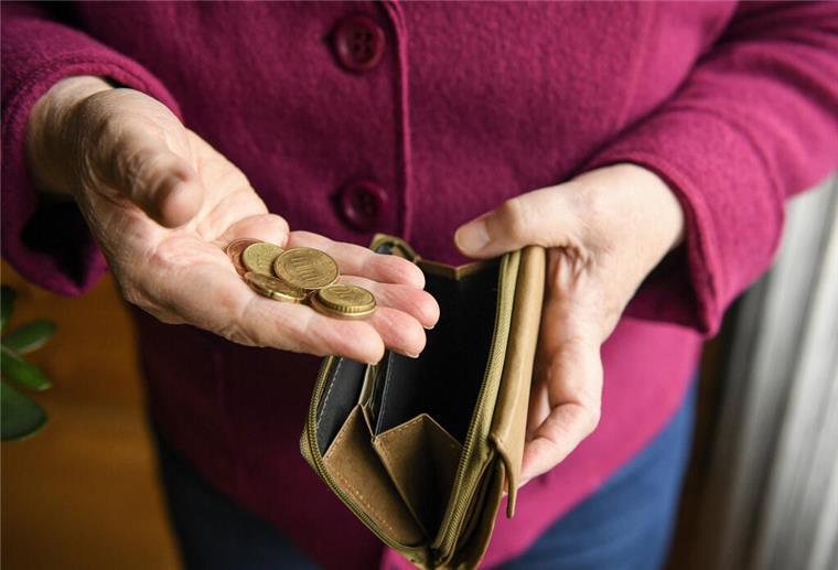 Eine Seniorin durchsucht einen Mülleimer.