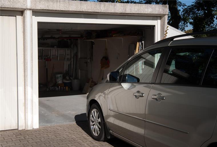 Ein silbernes Auto steht vor einer Garage.