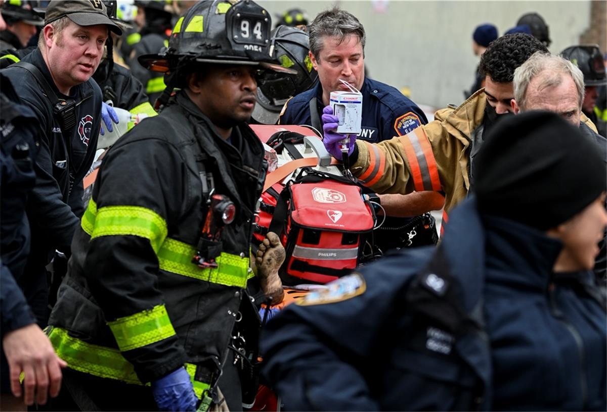 Rettungskräfte bringen ein Brandopfer während eines Hochhausbrandes in der East 181 Street im New Yorker Stadtbezirk Bronx in einen Krankenwagen. 