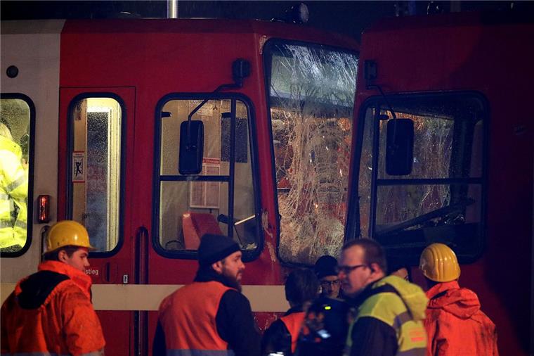 Rettungskräfte stehen vor den beiden Straßenbahnen, die in Köln zusammengestoßen sind. 