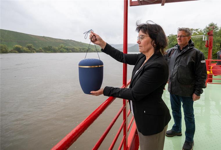 „Letzte Reise“ auf einem Fluss? Was das neue Bestattungsgesetz erlaubt Eine Frau steht an der Rehling eines Schiffes und hält eine Urne in der Hand.