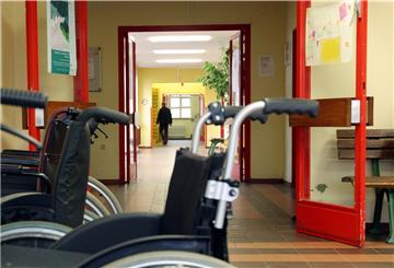 Rollstühle stehen vor einer Brandschutztür in einer Werkstatt für behinderte Menschen. Verbände kritisieren, dass diese besonders gefährdeten Menschen nicht früher gegen Corona geimpft werden.