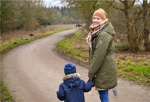 Eine Frau mit Kind auf steht auf einem Feldweg.