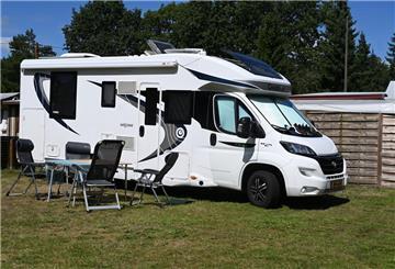 Ein Wohnmobil mit Tisch und Stühlen im Außenbereich steht auf dem Waldcampingplatz in Hepstedt.