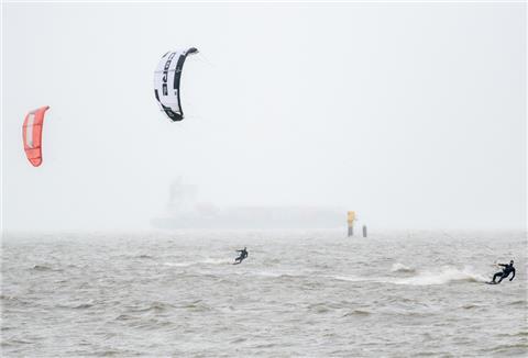 Mehrere Kitesurfer sind bei stürmischem Wetter auf der Nordsee unterwegs.
