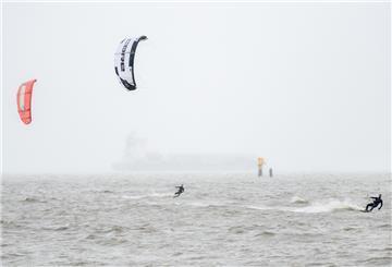 Mehrere Kitesurfer sind bei stürmischem Wetter auf der Nordsee unterwegs.