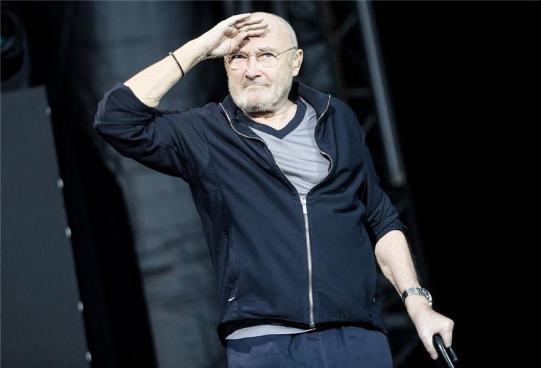 Popsänger Phil Collins steht auf der Bühne.