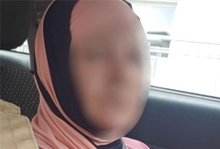 Eine Frau mit Kopftuch sitzt in einem Auto und blickt in die Kamera.