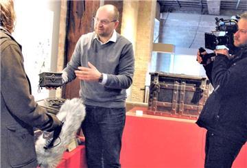 Sammler Alexander Kollmann mit Ausstellungsstücken und einem Filmteam