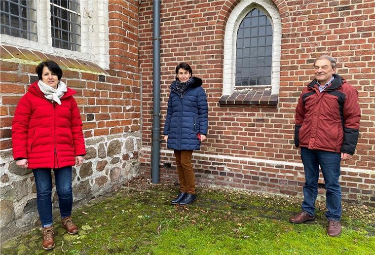 Sandra Fitter, zweite Vorsitzende des Kirchenvorstands, Pastorin Pia Werner und Helmut Blohm, erster Vorsitzender, neben einem provisorischen Fallrohr, dass eine Dachdeckerfirma vorerst installiert hat.
