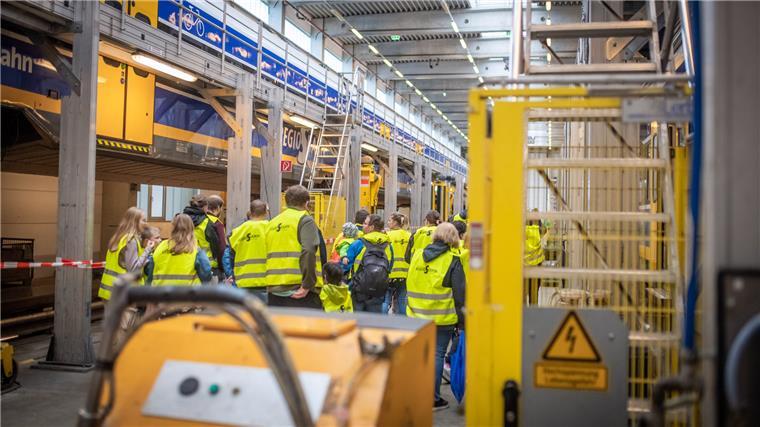 Schaulusitige iin Sicherheitswesten dürfen sich in der Wartungshalle der Nordwestbahn in Bremerhaven umsehen und auch mal einen Zug von unten inspizieren.