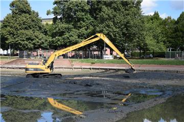 Schaufelweise wird der Schlamm aus dem Holzhafen in Bremerhaven an den Beckenrand gekippt. Dort soll er abtrocknen. Anschließend wird der Modder abgefahren.