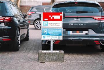 Parkende Autos und ein Hinweisschild auf einen Kundenparkplatz