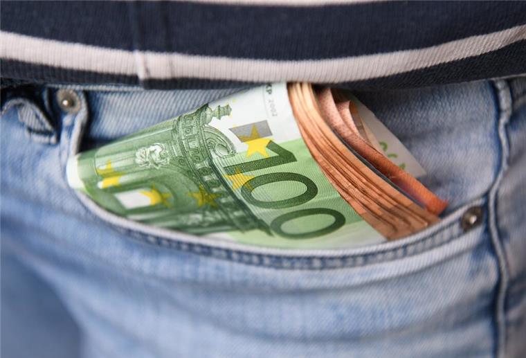 Plötzliches Aus! Merz-Regierung schafft 100-Euro-Zuschuss ab Geldscheine stecken in einer Hosentasche.
