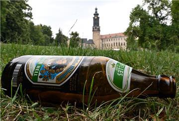 Eine leere Bierflasche liegt im Park. Für Gärtner gibt es einen genialen Bierflaschen-Trick bei der richtigen Einstellung des Rasenmähers. 