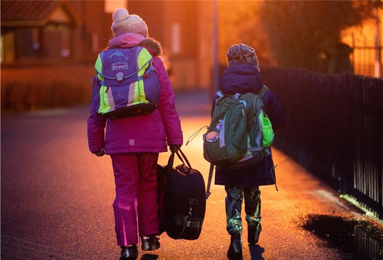 Zwei Schüler gehen am frühen Morgen auf dem Schulweg zu ihrer Grundschule in der Region Hannover. 
