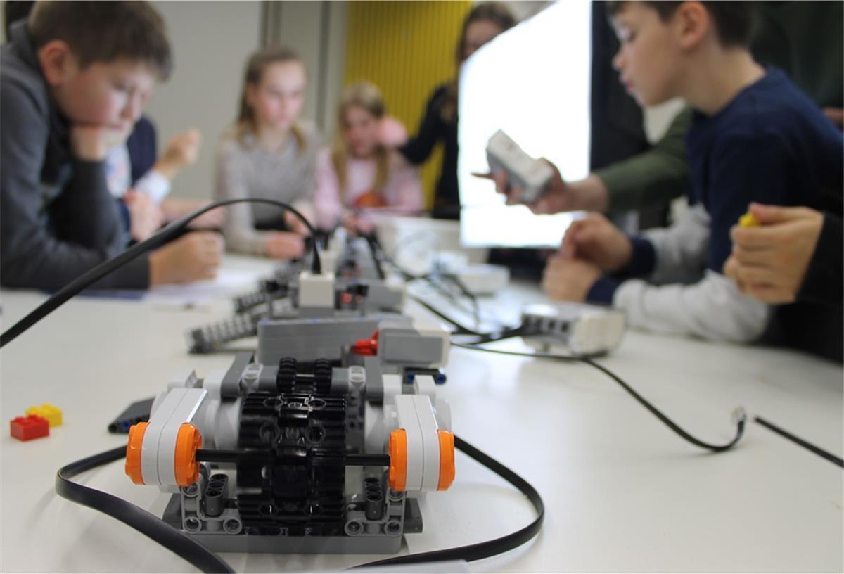 Schülerinnen und Schüler programmieren ein Fließband zum Sortieren von Lego-Steinen.