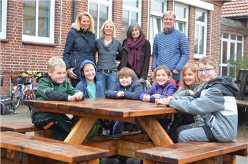Schulleiterin Barbara Marherr (stehend, Zweite von links) und die Kinder der Grundschule Wilstedt freuen sich über die Bank-Tische, die für Unterricht unter freiem Himmel bestimmt sind. Ermöglicht haben den Kauf unter anderem der Förderverein der schule und die Wilstedter Bürgerstiftung. 