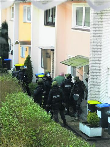 Schwer bewaffnete und maskierte Polizisten holen den Mann aus seinem Haus. 