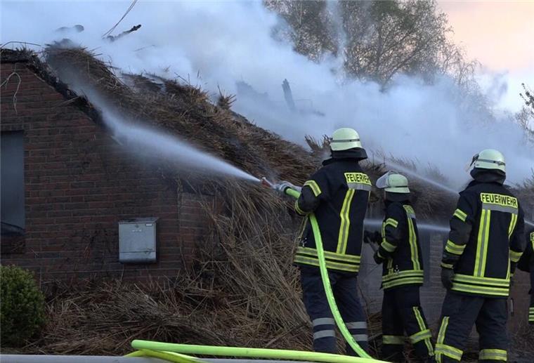 Feuerdrama: Reetgedecktes Haus wird Opfer der Flammen Feuerwehrleute bekämpfen mit Schläuchen ein brennendes Reetdachhaus.